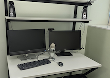 A modern virtual meeting booth with dual monitors, a ring light, microphone, keyboard, and mouse, designed for efficient virtual communication.